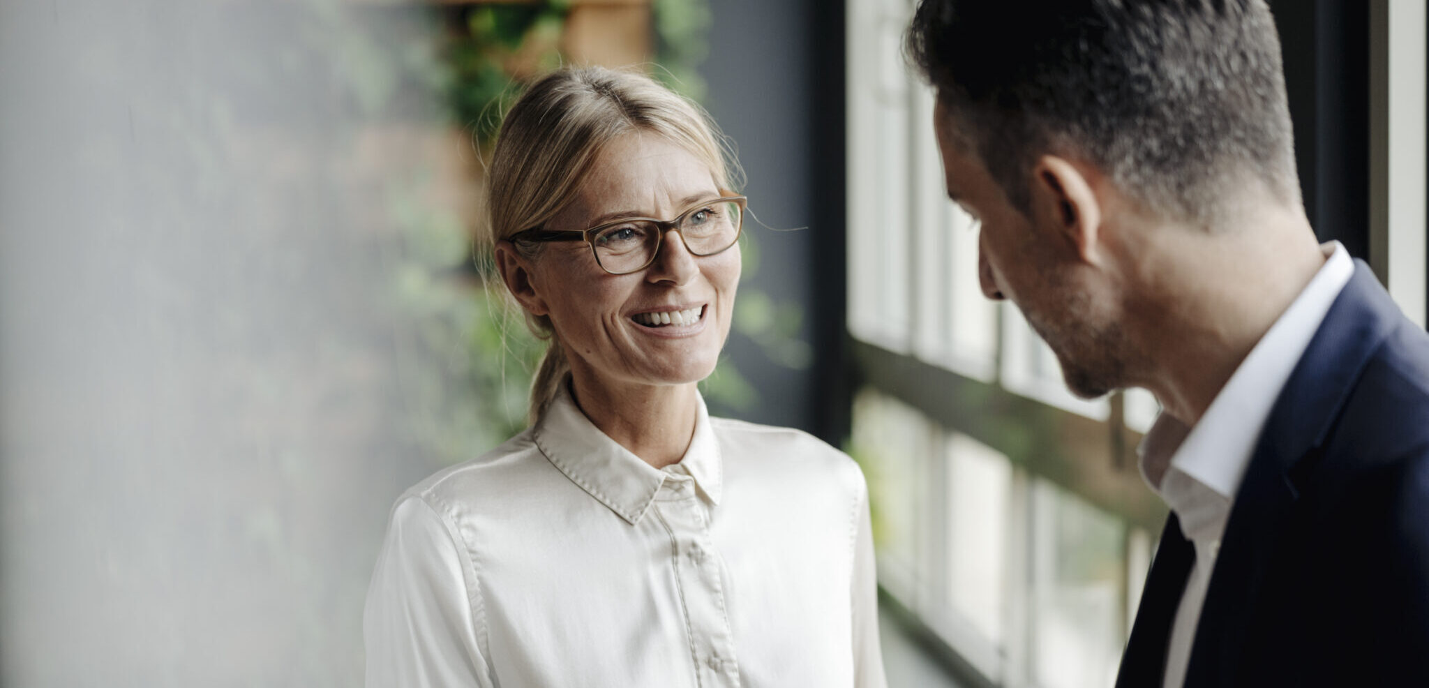 Une femme souriante discutant avec un homme dans un cadre professionnel