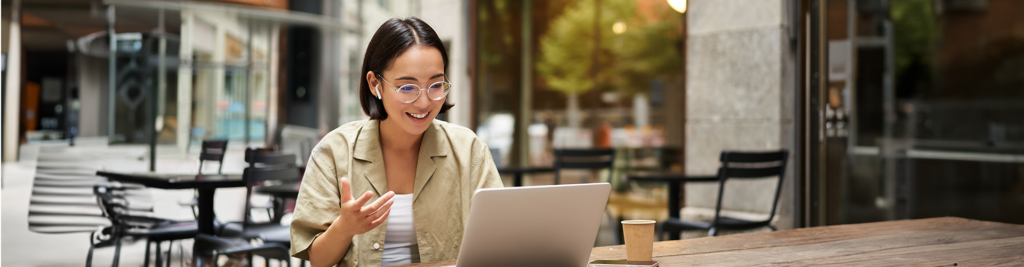 Une jeune femme sur la terrasse d'un café devant son ordinateur - Épargne salariale et retraite